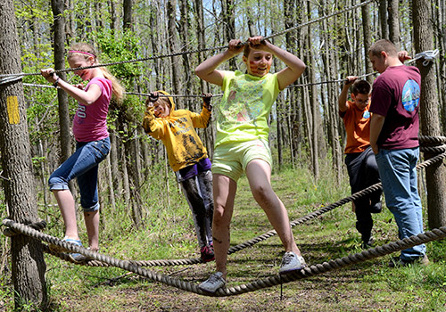 Kids walking along ropes course on forest trail