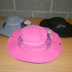 Three sun hats, in different colors, with Marshy Point name on front