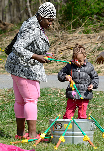 Adult and child using plastic poles to catch pretend fish in tub