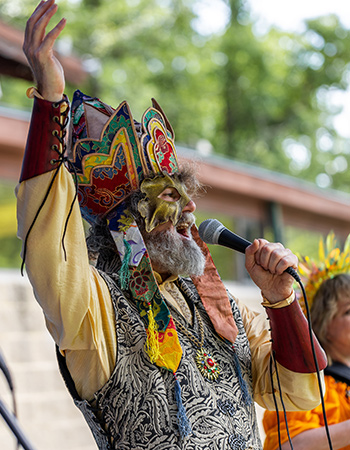 Man in costume talking into microphone with one hand raised